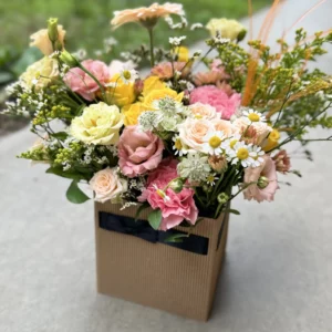 Arrangement floral Le Cubique, composé de fleurs frâiches dans les tons rose et jaune selon fleurs de saison